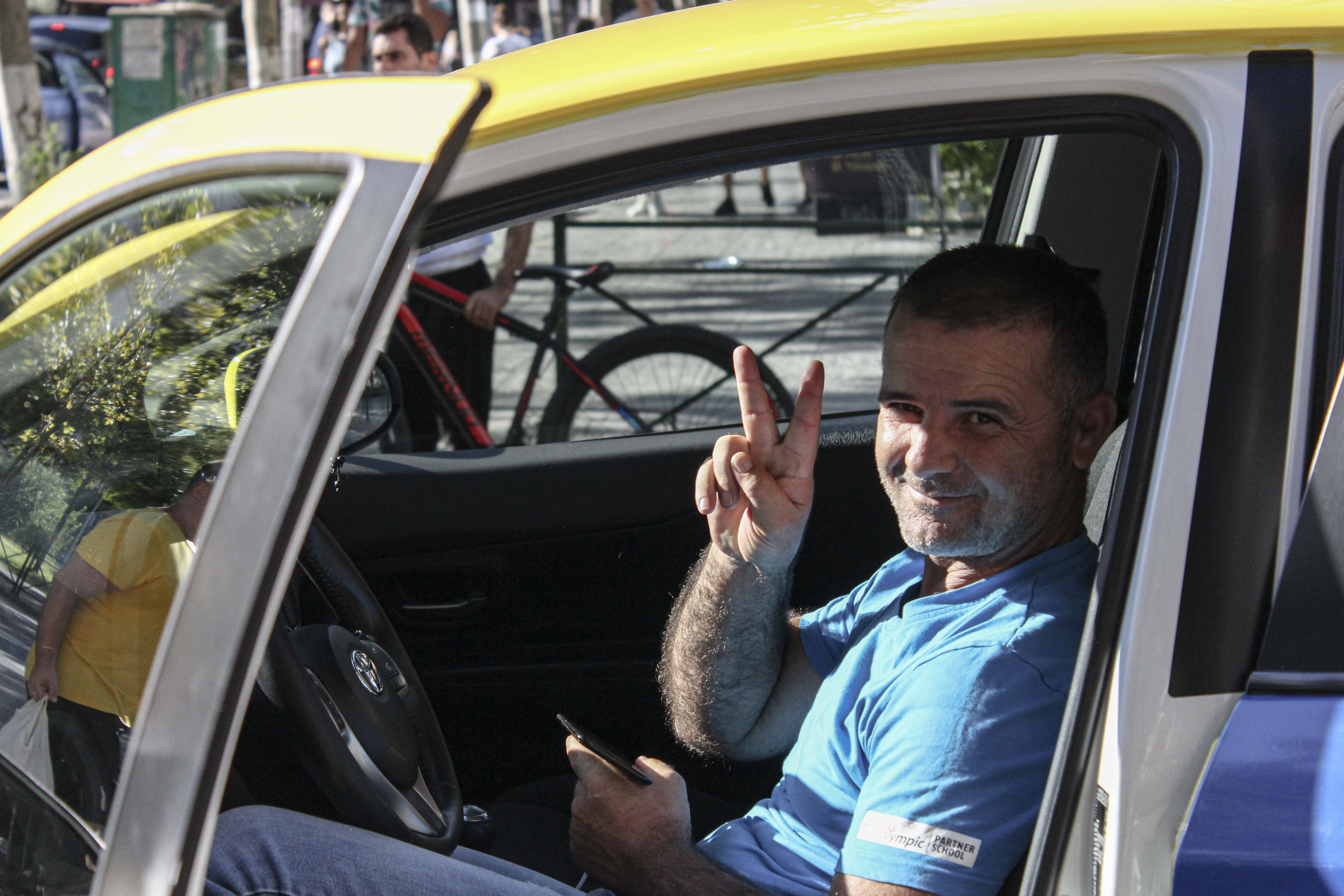 A taxi driver poses for the camera during his break on the street of downtown Tirana, Albania on Thursday, Aug. 27, 2020. (Photo by Meng Wei)
